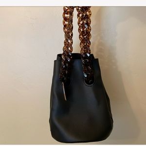 Black bucket bag with tortoise chain handles